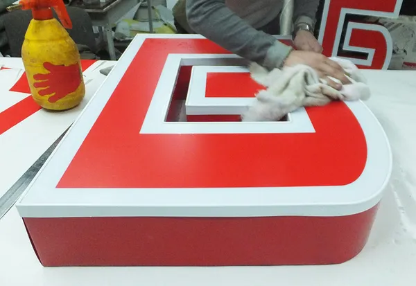 Процесс сборки крупногабаритной световой буквы в производственном цехе.